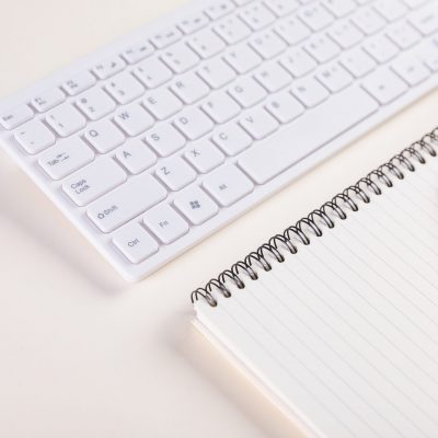 A closeup of a keypad and a notepad with pen on a white table - concept of job