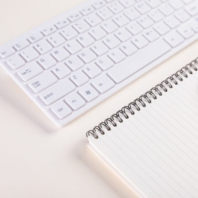 A closeup of a keypad and a notepad with pen on a white table - concept of job